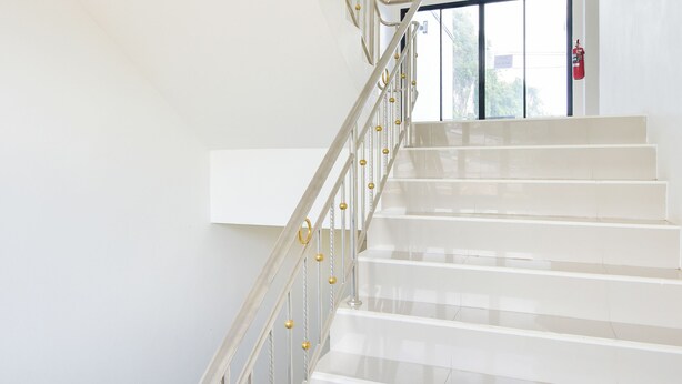 Una escalera con escalones blancos y una barandilla de metal con detalles dorados.