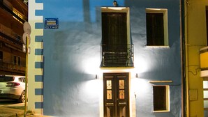 Ein zweistöckiges Gebäude mit blauer Fassade, einem sichtbaren Schild, das einen Parkplatz kennzeichnet, und einem kleinen Balkon.