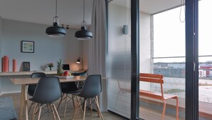 A modern dining area with a wooden table, black chairs, and pendant lights. - Bett & Bude Boardinghouse (Sylt)