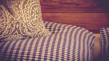 A checkered sofa with a patterned pillow against a wooden wall.