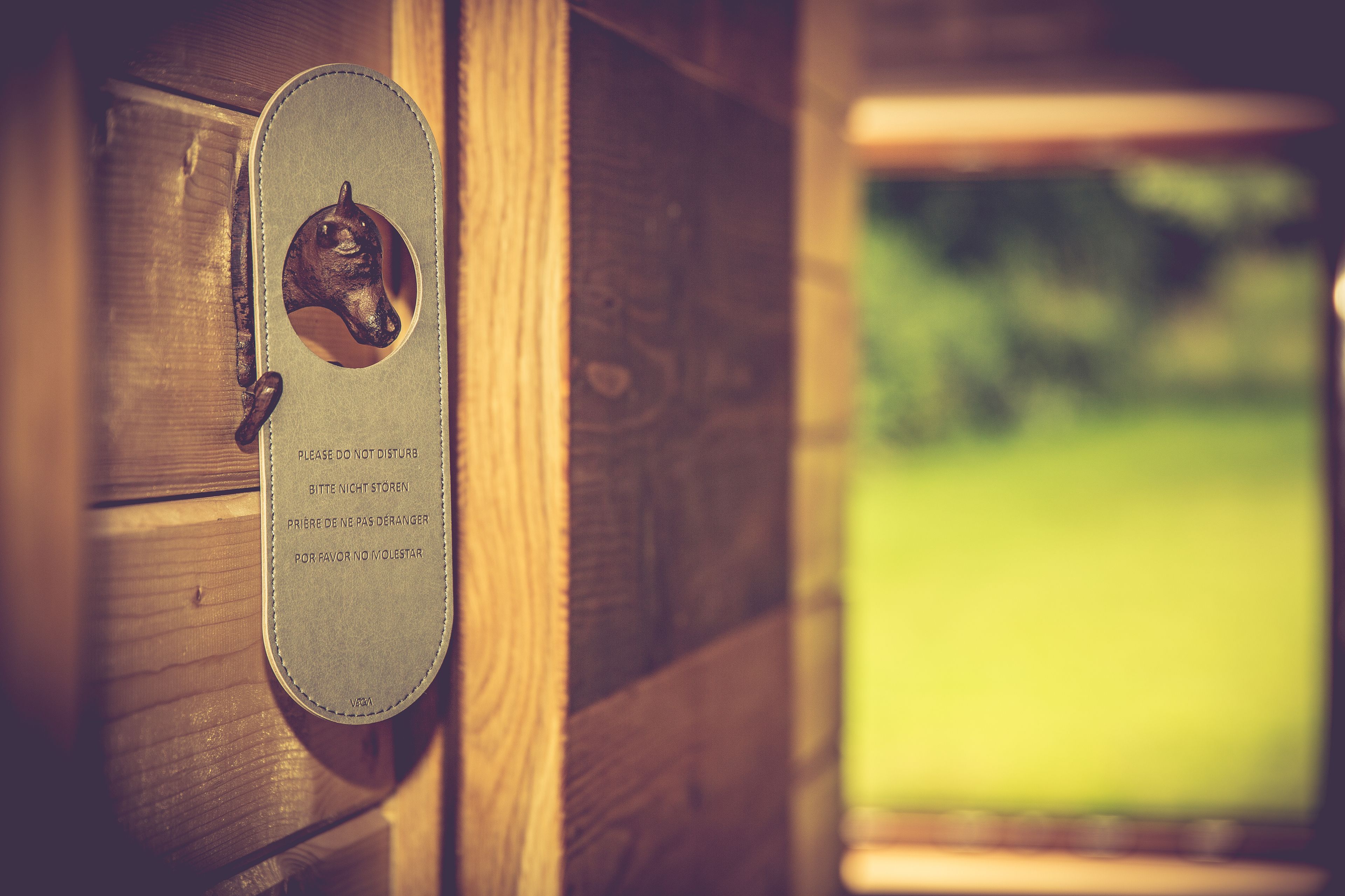 A wooden door with a metal plaque featuring a horse head and text in multiple languages.