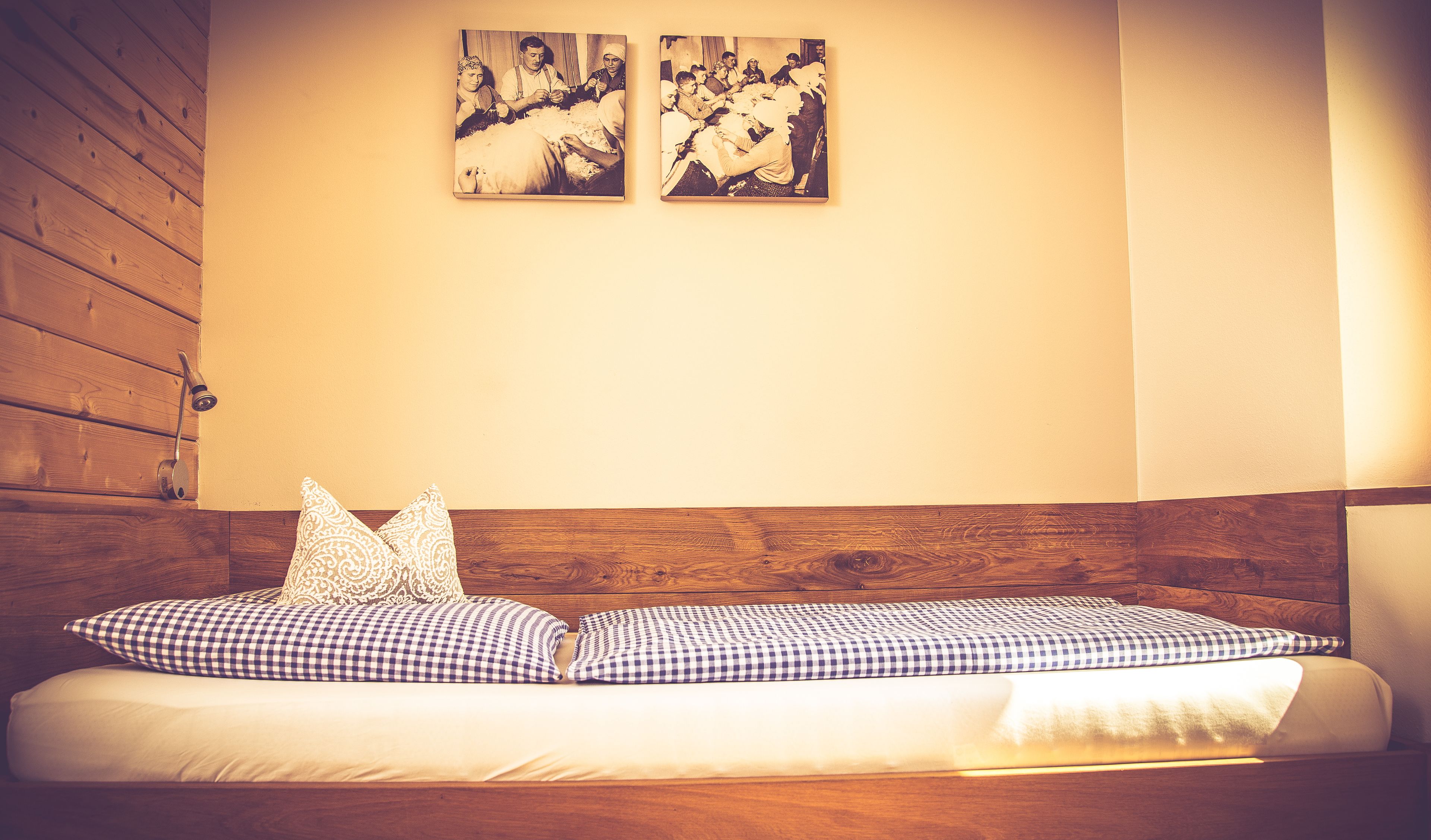 Una cama individual con cabecera de madera y dos cuadros colgados en la pared.