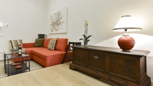 A living room with a sofa, a coffee table, a lamp, a radiator, and a painting on the wall.