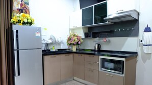 A modern kitchen with a refrigerator, microwave, and oven. - Sirimongkol Resort (Surat Thani)