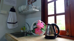 A kitchen with a wooden countertop, a sink, a kettle, and a window with a view of greenery. - Sirimongkol Resort (Surat Thani)