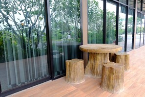 Un interior moderno con una mesa redonda de madera y taburetes a juego, amplias ventanas con vistas al exterior lleno de vegetación.