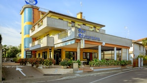 Un hotel con una torre central, un restaurante a nivel de la calle y un edificio de dos pisos con balcones.