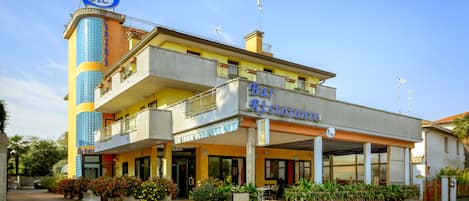 Een hotel met een centraal torentje, een restaurant op de begane grond en een gebouw met twee verdiepingen en balkons.