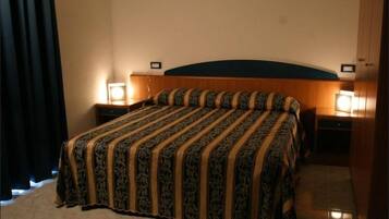 A neatly made bed with a patterned bedspread, two bedside lamps, and a wooden headboard.