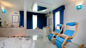 Un baño moderno con bañera, una silla azul y un tocador con espejo.