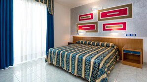 Habitación de hotel con una cama grande, cabecero de madera, mesita de noche e iluminación decorativa en la pared.