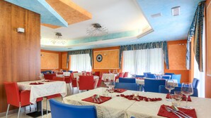 Un restaurante con varias mesas, sillas rojas y azules, y un techo de diseño singular.