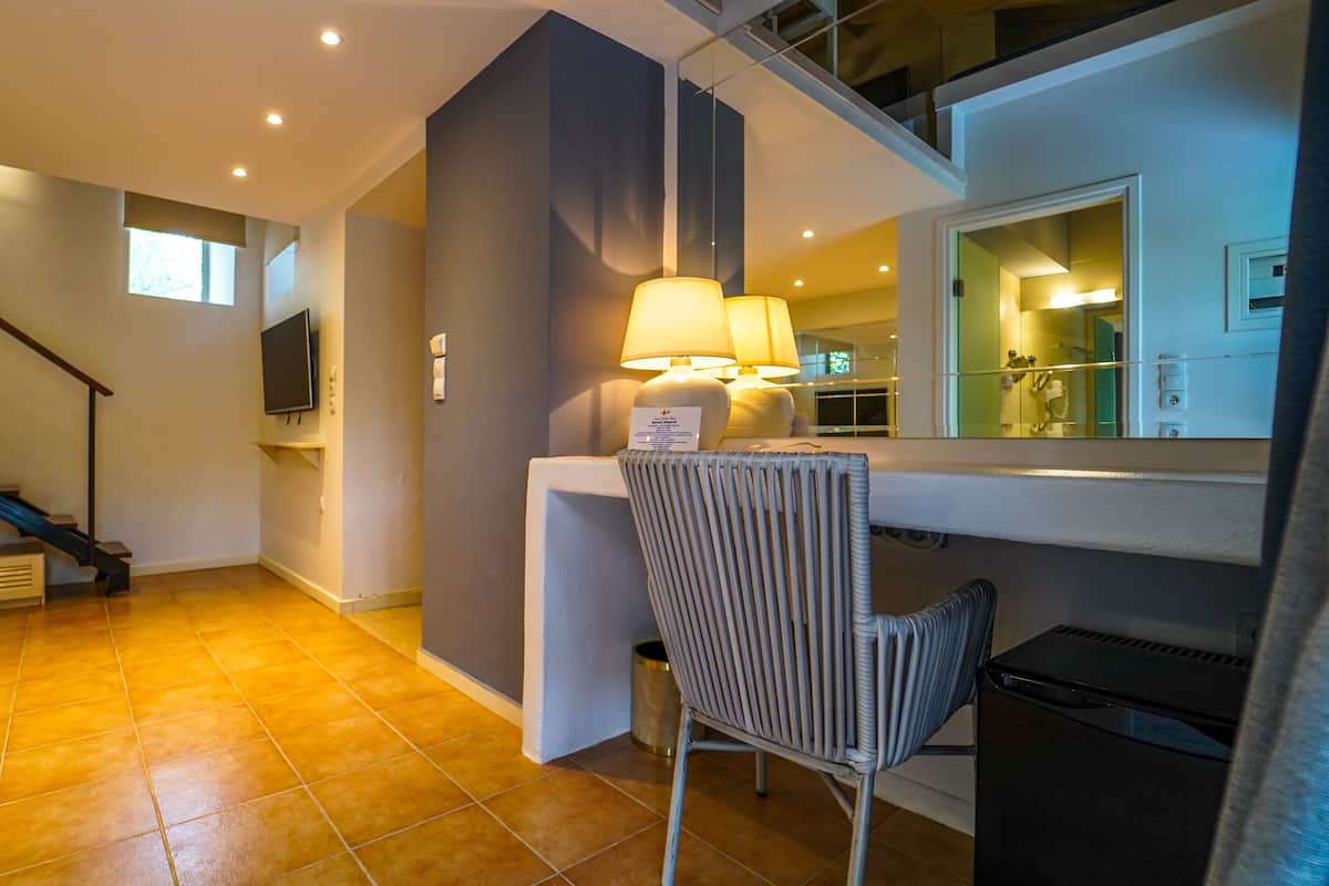 Un salon moderne avec un escalier, un téléviseur à écran plat, une lampe et un fauteuil.