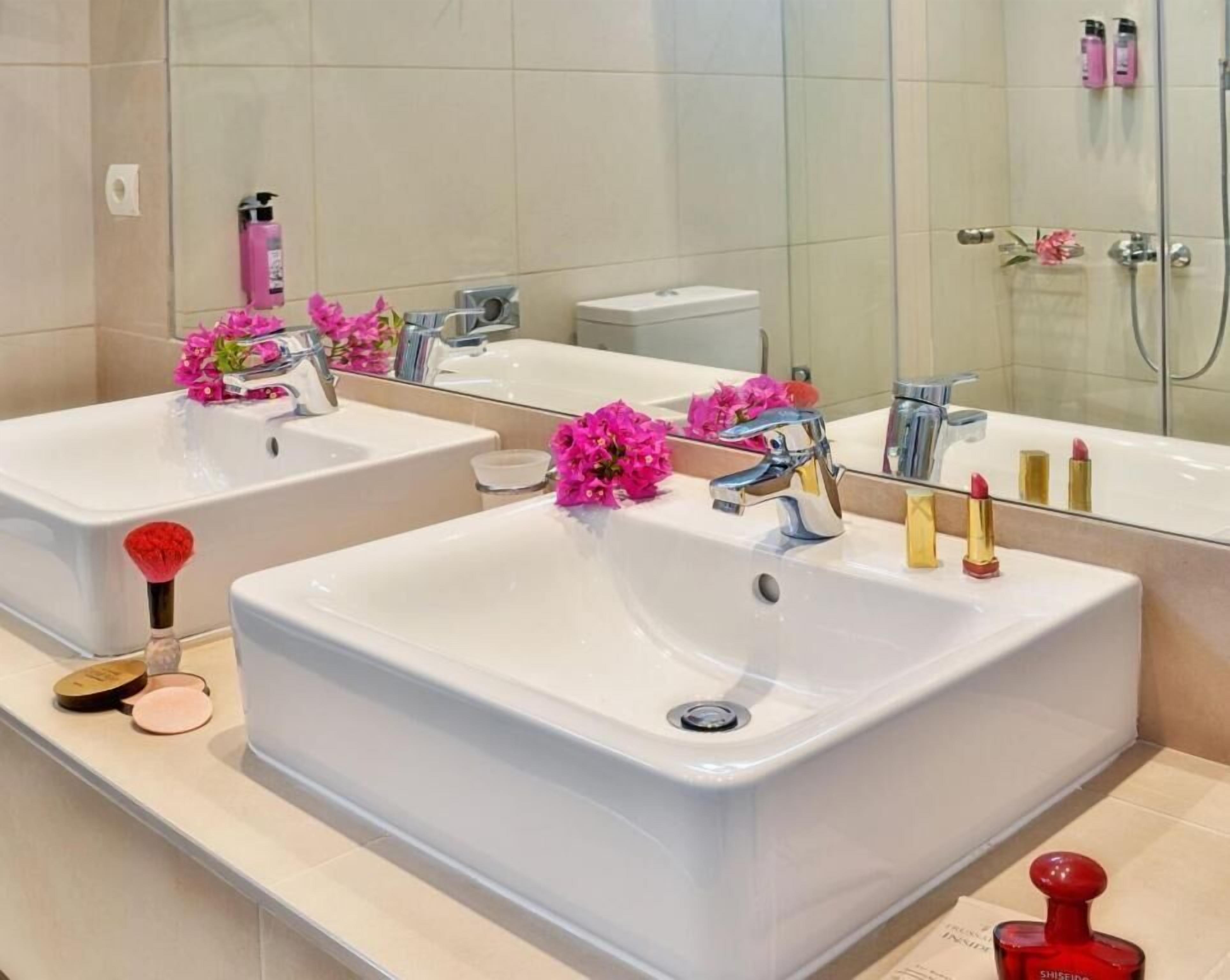 A bathroom with two sinks, a mirror, and toiletries.