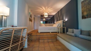 Una camera da letto moderna con un letto, un divano, una sedia e un'area pranzo con tavolo e sedie.