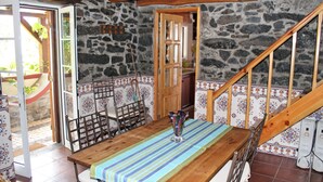 A rustic dining area with a wooden table, chairs, and a stone wall backdrop. - Stonecliff Cottage by Our Madeira (Calheta)