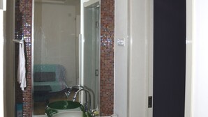 Une salle de bain avec un lavabo blanc, un miroir et un espace douche.