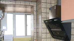 Une cuisine de taille réduite équipée d’une cuisinière à gaz, d’un four encastré, d’une fenêtre et d’un réfrigérateur.