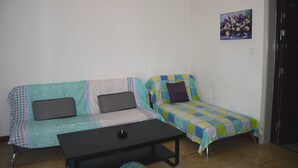 Une petite pièce meublée, comprenant deux canapés, une table basse et une porte.