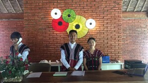 A reception desk with a brick wall background, a large decorative umbrella mural, and a vase of red roses.