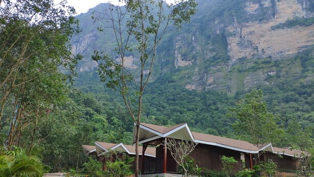 A resort with multiple bungalow-style buildings, a paved pathway, and lush greenery.