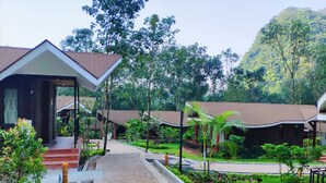 A pathway leading to a building with a modern design, surrounded by lush greenery and trees.