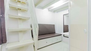 Een schone, moderne kamer met een witte bank, een spiegel en inbouwplanken.