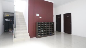 Un pasillo con una escalera, un zapatero y dos puertas con las indicaciones 105 y 104.