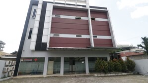 Un edificio de varios pisos con un diseño arquitectónico moderno, que presenta una combinación de paneles blancos y color burdeos.