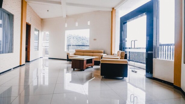 A spacious, modern living area with a large sofa set, a coffee table, and a view of a balcony. - RedDoorz near Taman Rekreasi Selecta (Batu)