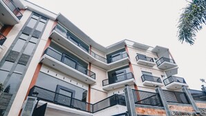 A multi-story building with balconies and a stone wall. - RedDoorz near Taman Rekreasi Selecta (Batu)