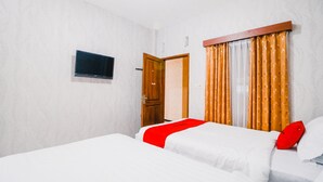A hotel room with two beds, a television mounted on the wall, and a door leading to another room. - RedDoorz near Taman Rekreasi Selecta (Batu)