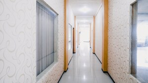 A long, narrow hallway with patterned walls and large windows on one side. - RedDoorz near Taman Rekreasi Selecta (Batu)