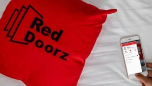 Un coussin rouge avec le texte « Red Doorz » sur un fond blanc.
