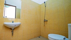 Une petite salle de bain avec des carreaux jaunes, un lavabo, des toilettes et un miroir.