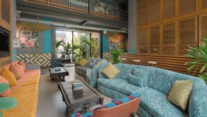 A spacious lobby with a high ceiling, a central seating area with sofas and armchairs, and a large wooden panel wall. - Sugar Marina Resort  Surf  Kata (Karon)