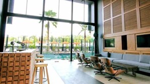 A modern indoor space with a pool view, seating area, and large windows. - Sugar Marina Resort  Surf  Kata (Karon)