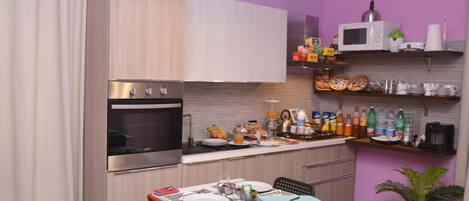 A compact kitchen with a microwave, oven, and various food items on the counter.