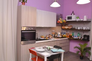 Uma cozinha compacta com micro-ondas, forno e diversos alimentos sobre o balcão.