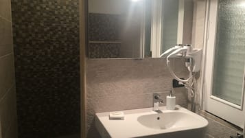 Une salle de bain avec un lavabo blanc, un miroir à main et un sèche-cheveux.