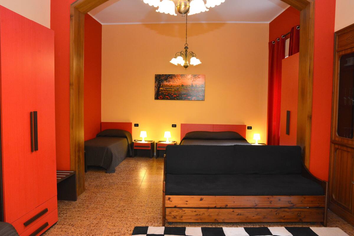 A room with two beds, a wooden headboard, a painting on the wall, and a chandelier.