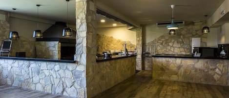 A kitchen with stone walls, wooden flooring, and pendant lighting.