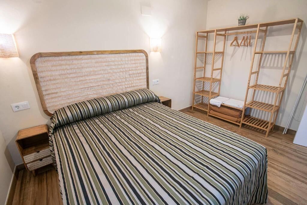 A room with a bed, bedside tables, a wardrobe, and a wall-mounted shelf.