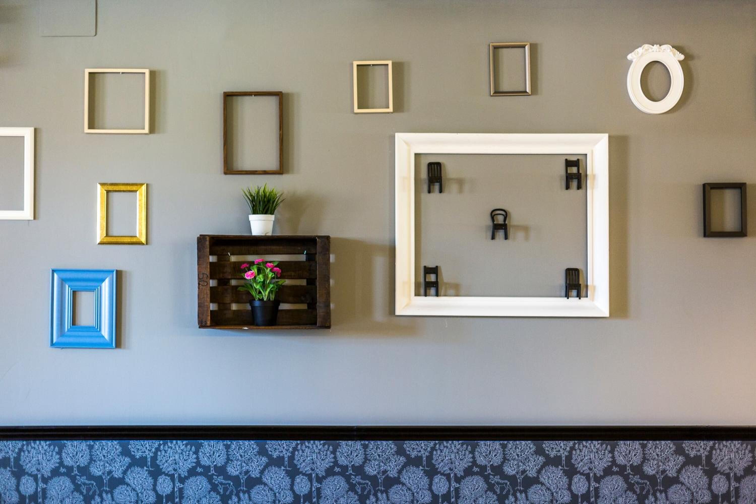 A wall with various framed pictures and a mirror.