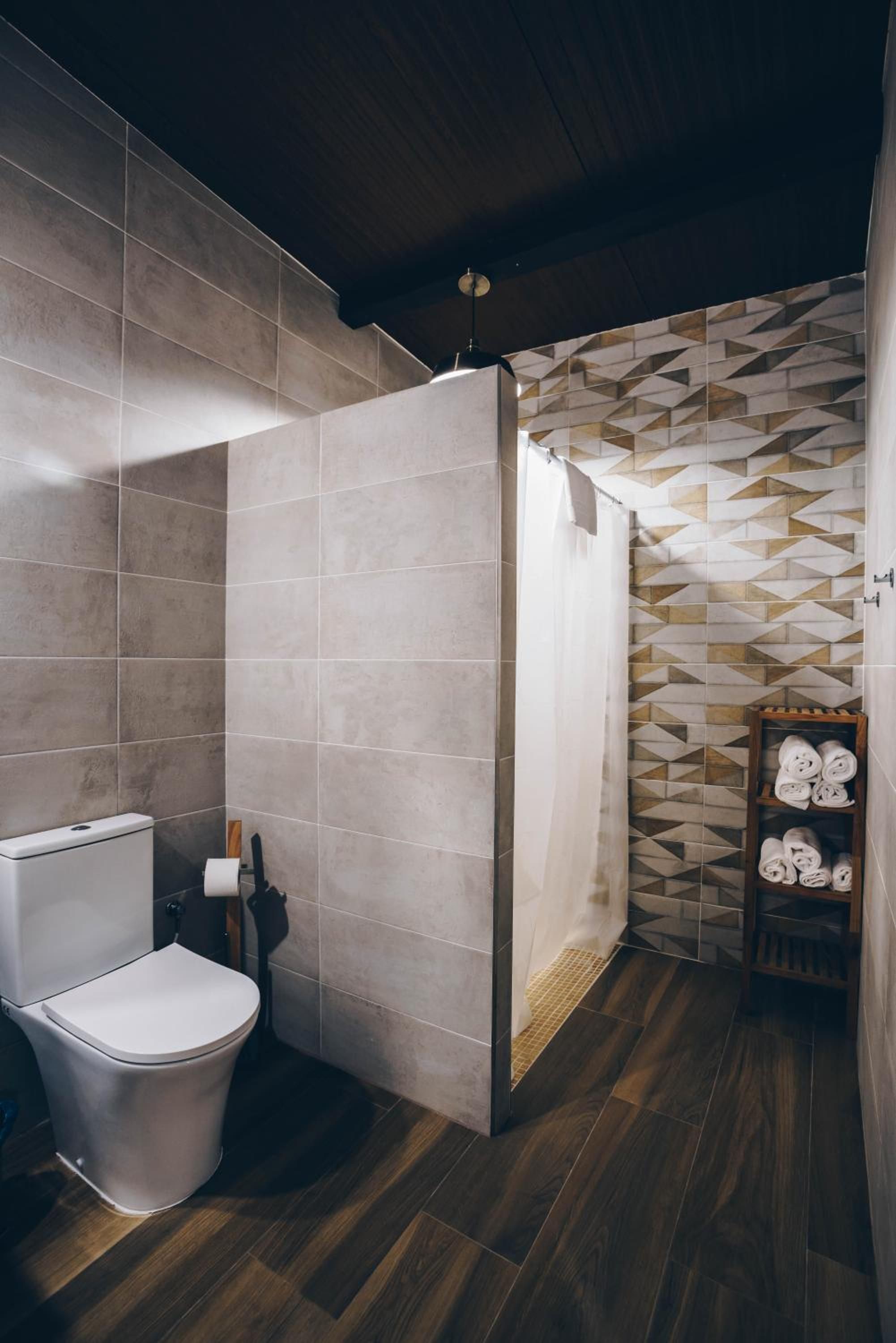 A modern bathroom with a toilet, shower, and wooden floor.