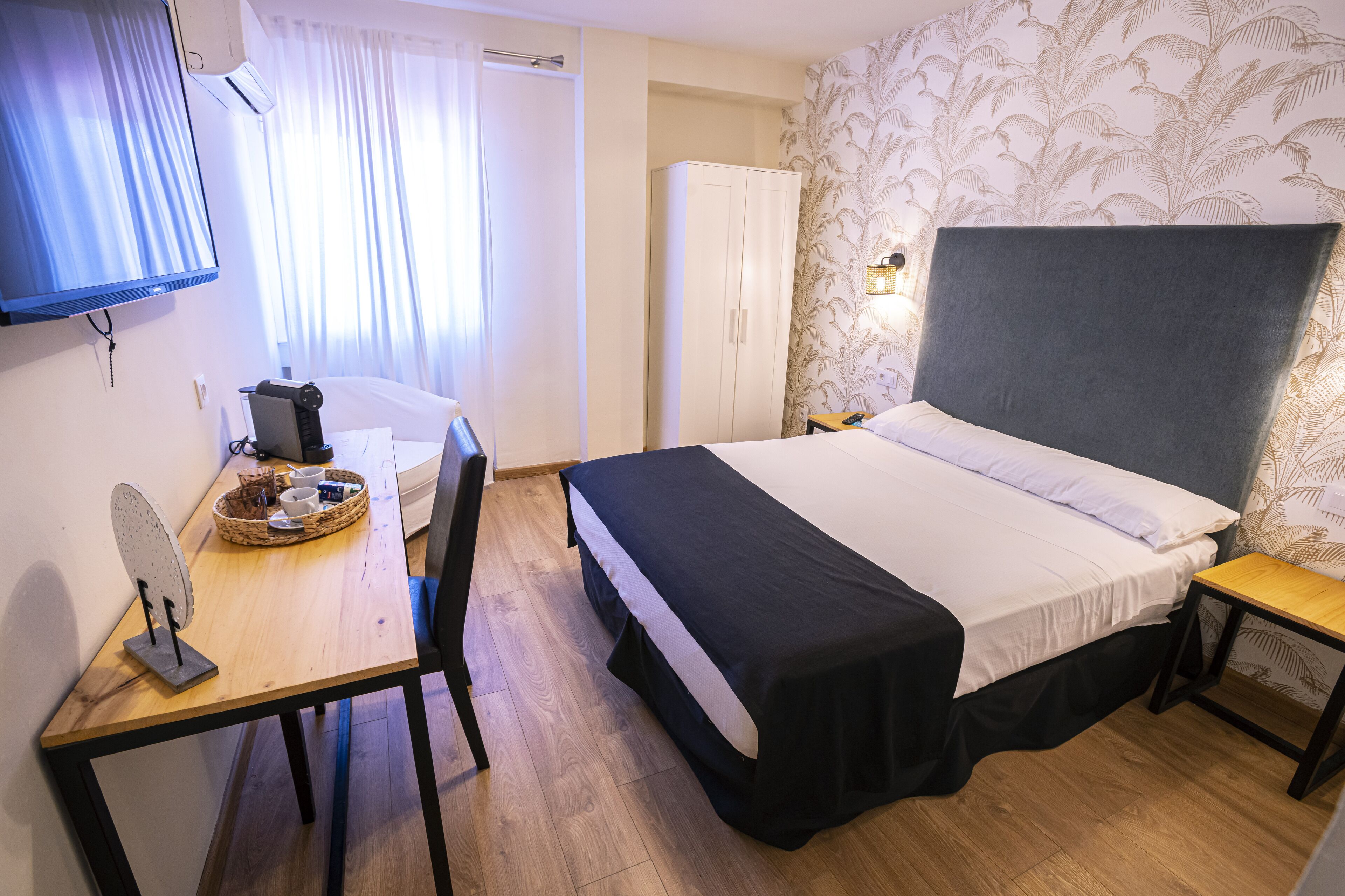 Une chambre d’hôtel comprenant un lit, un bureau avec un panier, une chaise, une armoire et un téléviseur.