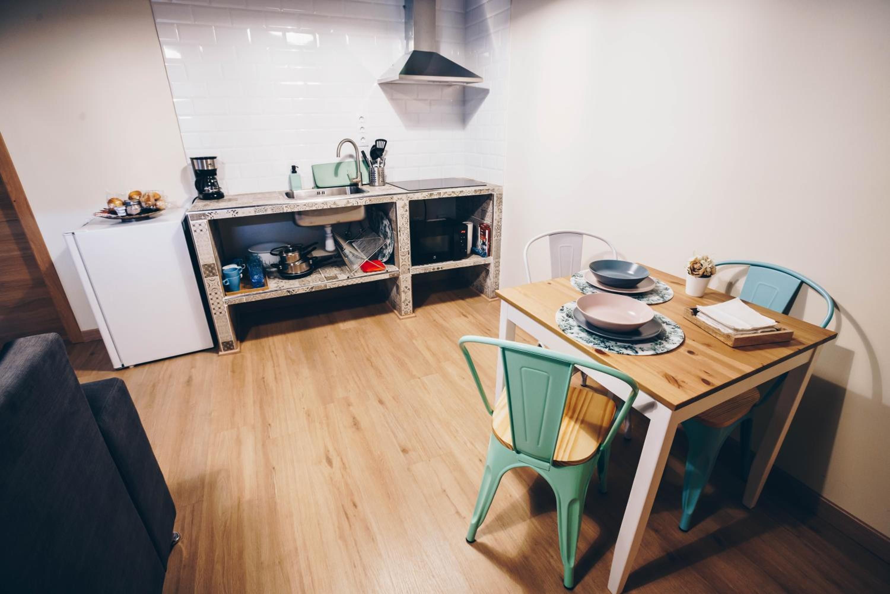 Une cuisine compacte équipée d’un réfrigérateur, d’un évier et d’un coin repas avec une table et des chaises.