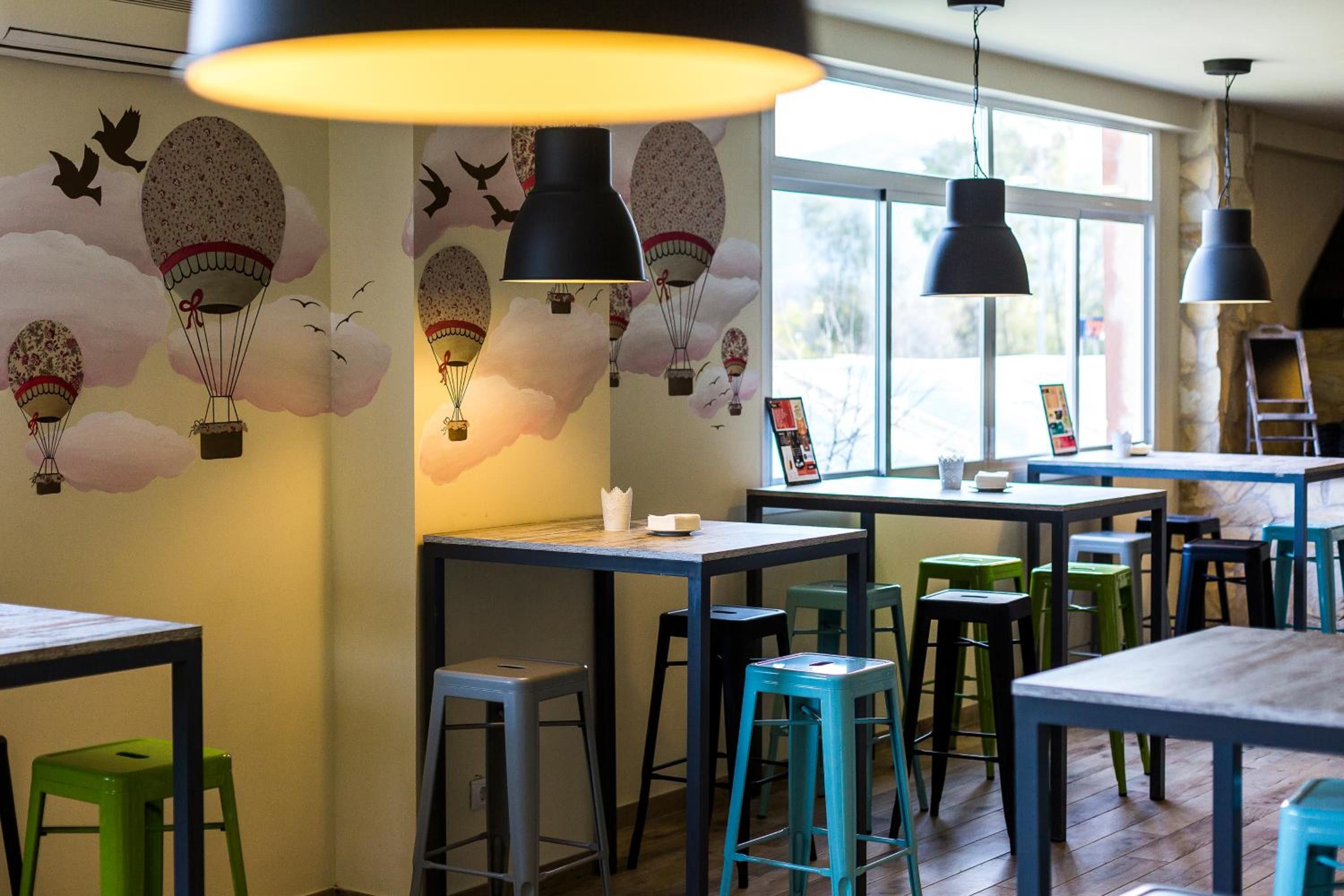 A restaurant interior with tables, chairs, and a mural of hot air balloons.