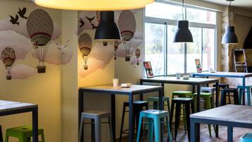 A restaurant interior with tables, chairs, and a mural of hot air balloons.