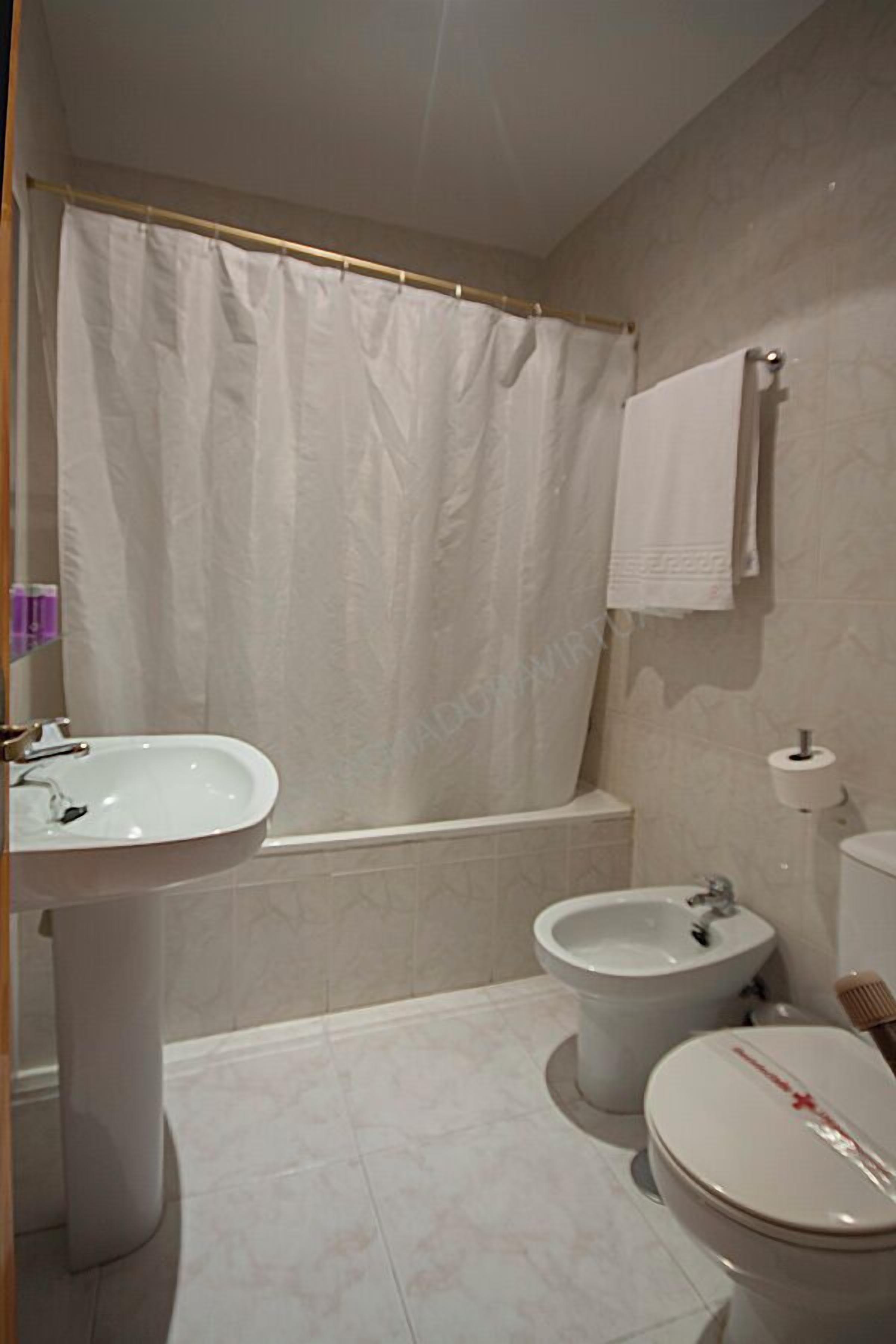A bathroom with a bathtub, a sink, a bidet, and a toilet.